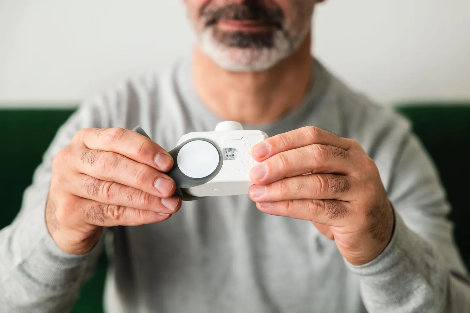 A close-up of a man using a handheld air quality analyzer, focusing on health and technology.