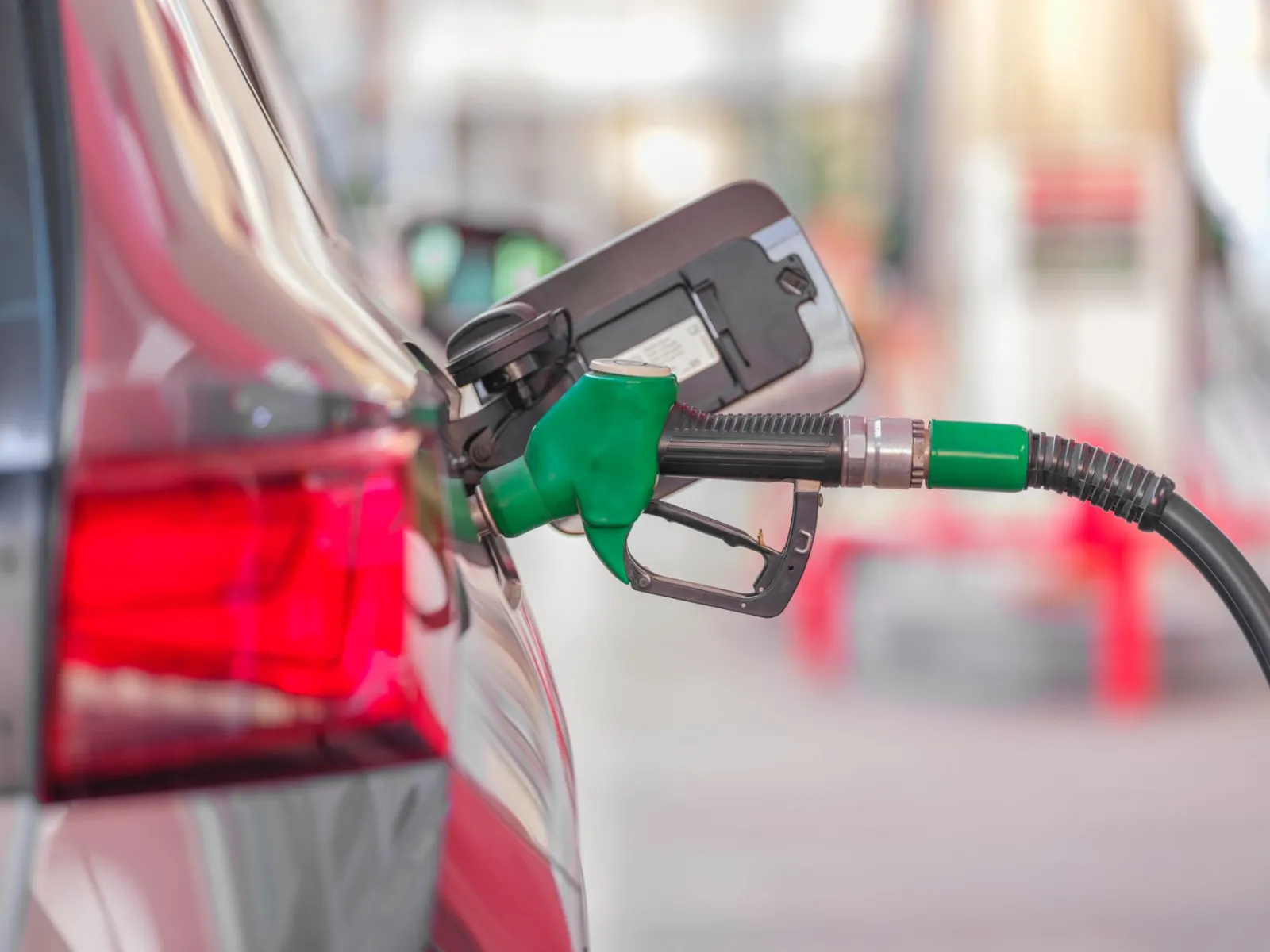 A close-up view of a fuel pump nozzle inserted into a car's tank at a gas station.